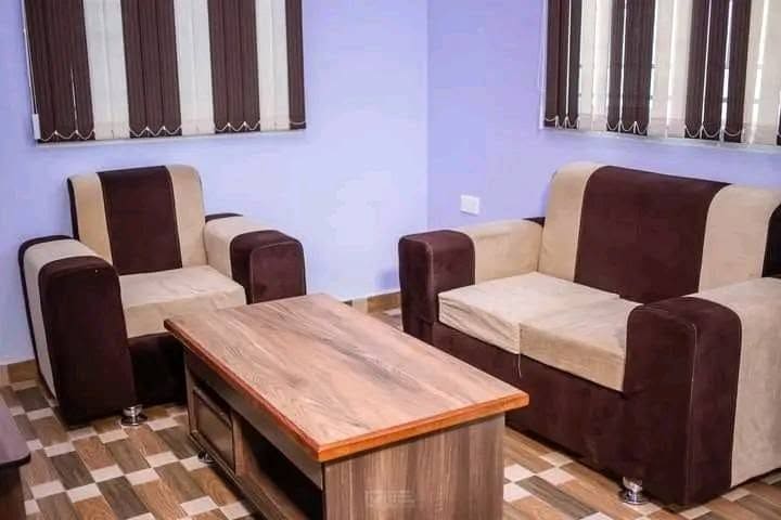 A sitting area inside a guest unit at Cherinas Homes, with two brown sofas and a wooden coffee table.