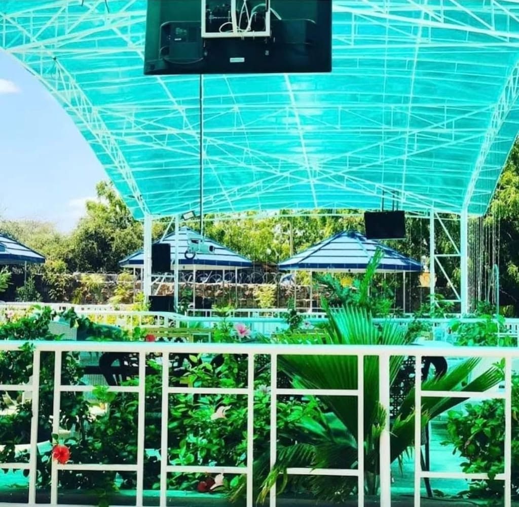 The pool area at Cherinas Homes under a green shade canopy, with gardens beyond.