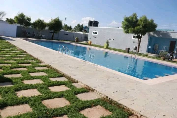 The long side of the pool at Cherinas Homes, with paving stones set in the lawn and the guest buildings beyond.