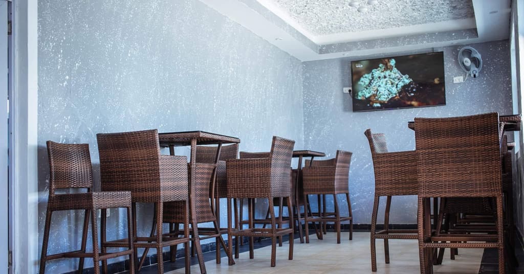 The restaurant seating at Cherinas Homes, with woven chairs, high tables and a wall-mounted TV.