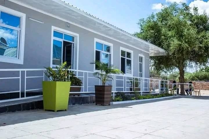 A row of guest rooms at Cherinas Homes with a covered terrace, potted plants and a paved forecourt.