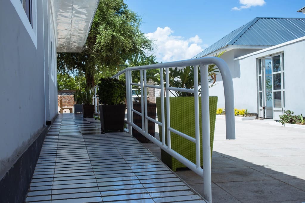 The terrace walkway along the guest rooms at Cherinas Homes in bright daylight.